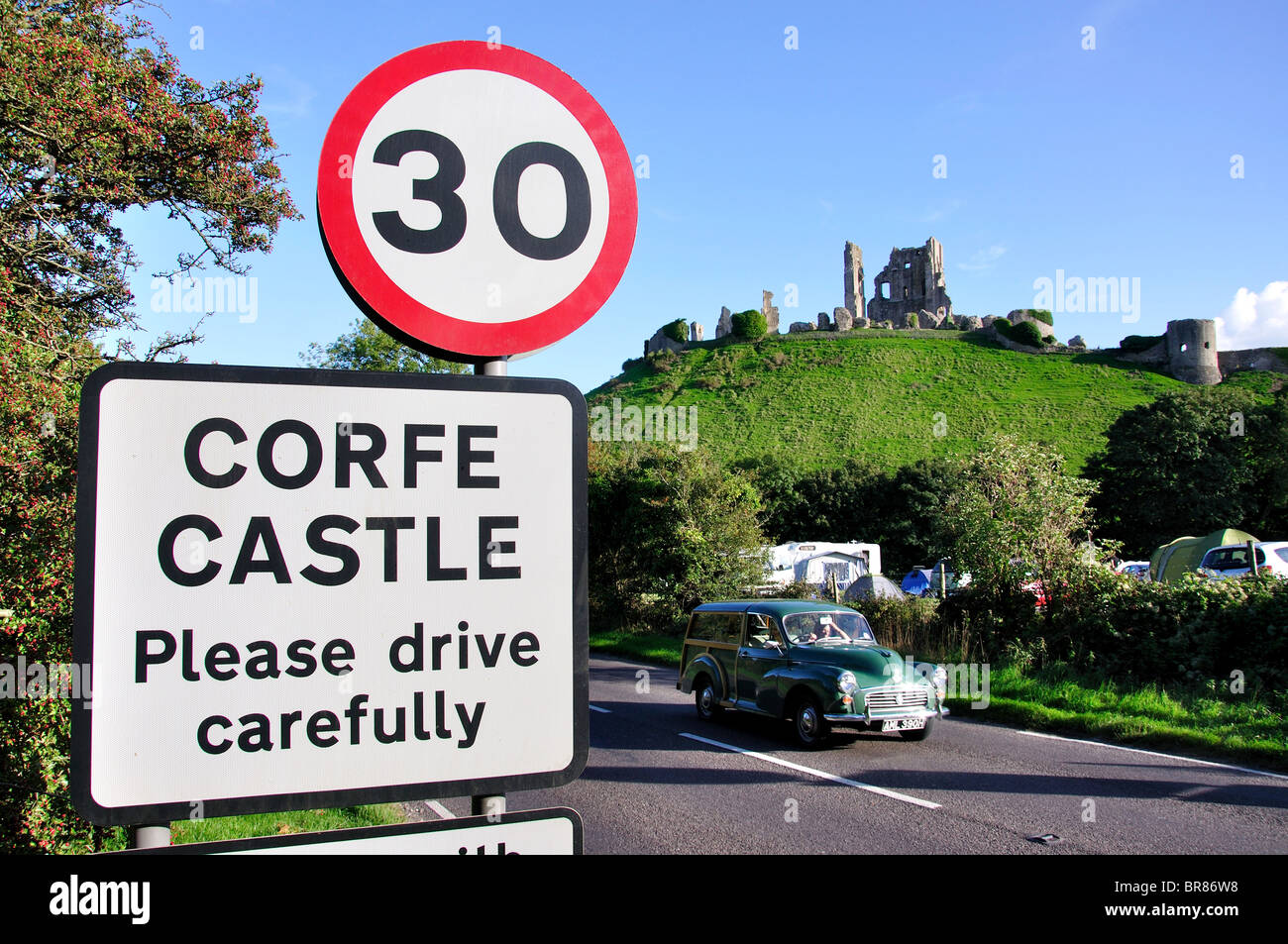 Ruins of Corfe Castle at sunset and village sign, Corfe Castle, Isle of Purbeck, Dorset, England, United Kingdom Stock Photo