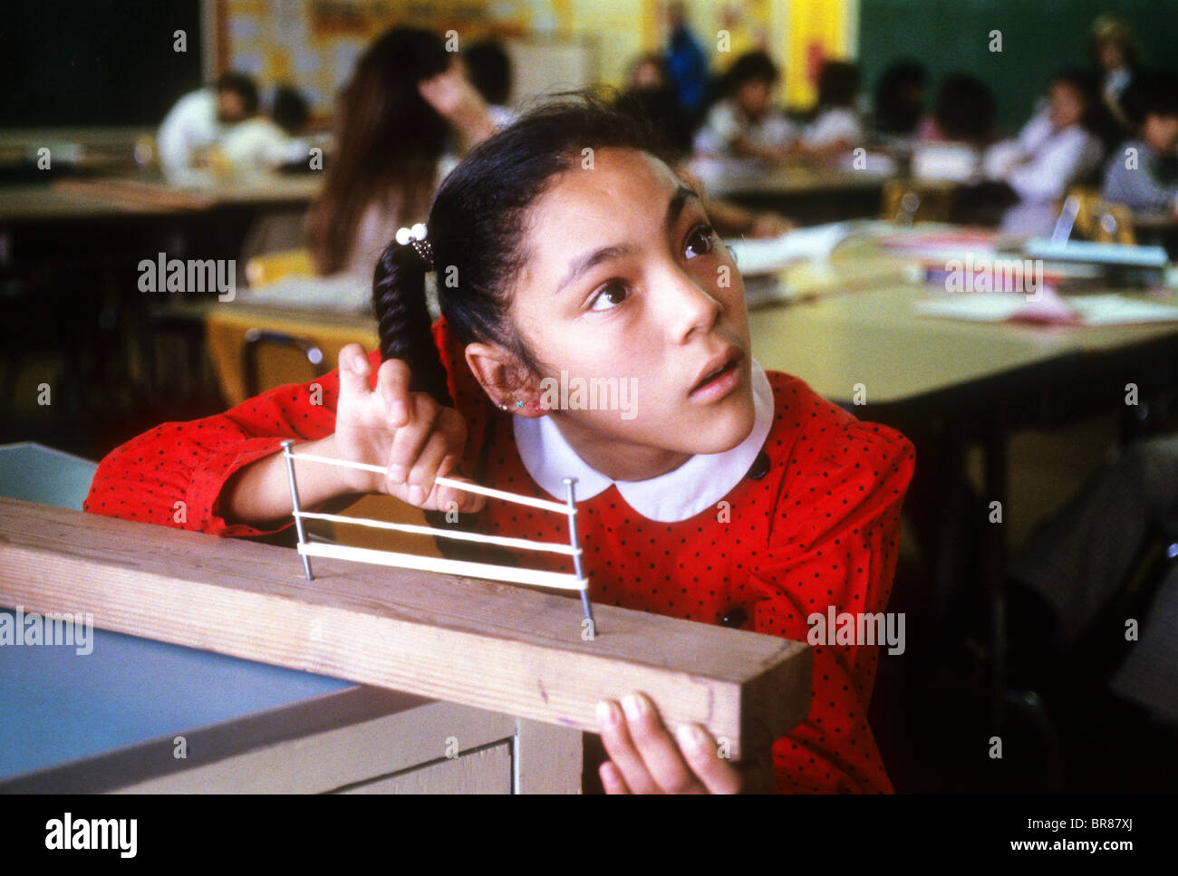 Hispanic girl student perform sound experiment with stretched rubber
