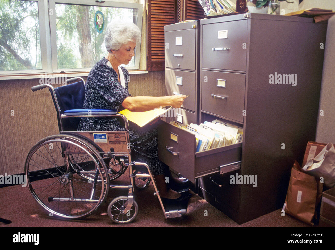 senior office worker secretary woman female wheel chair handicap work ...