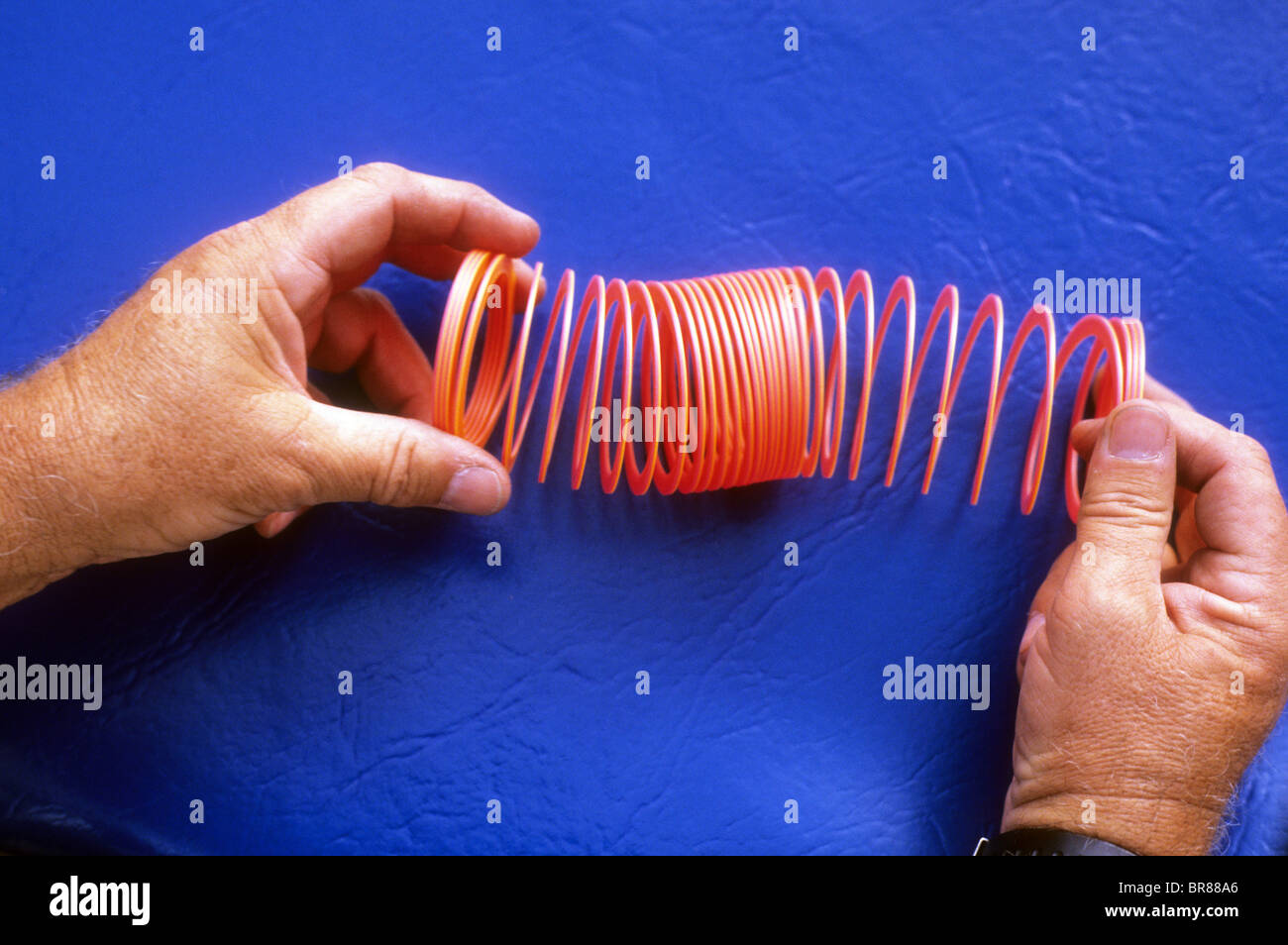 plastic slinky toy spring stretch coil wave effect pulse pattern force energy move science demo experiment Stock Photo