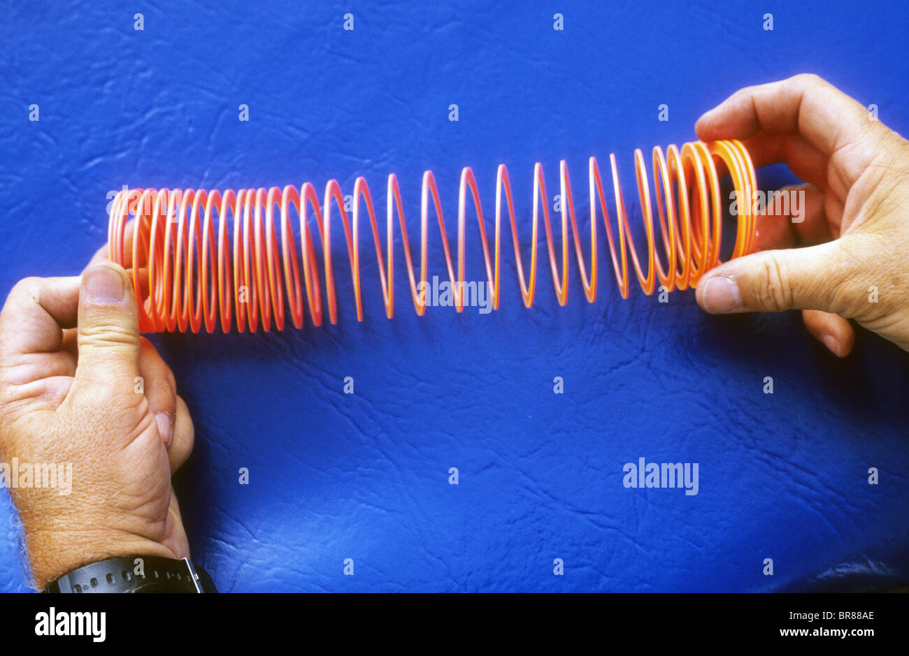 plastic slinky toy spring stretch coil wave effect pulse pattern force energy move science demo experiment Stock Photo