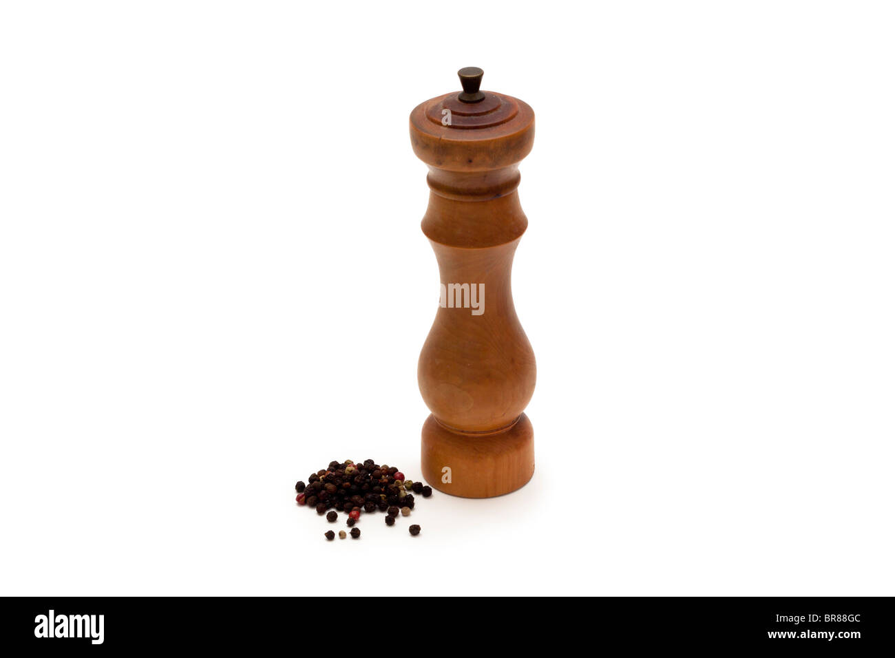 Wooden peppermill with mixed whole peppercorns on a white background