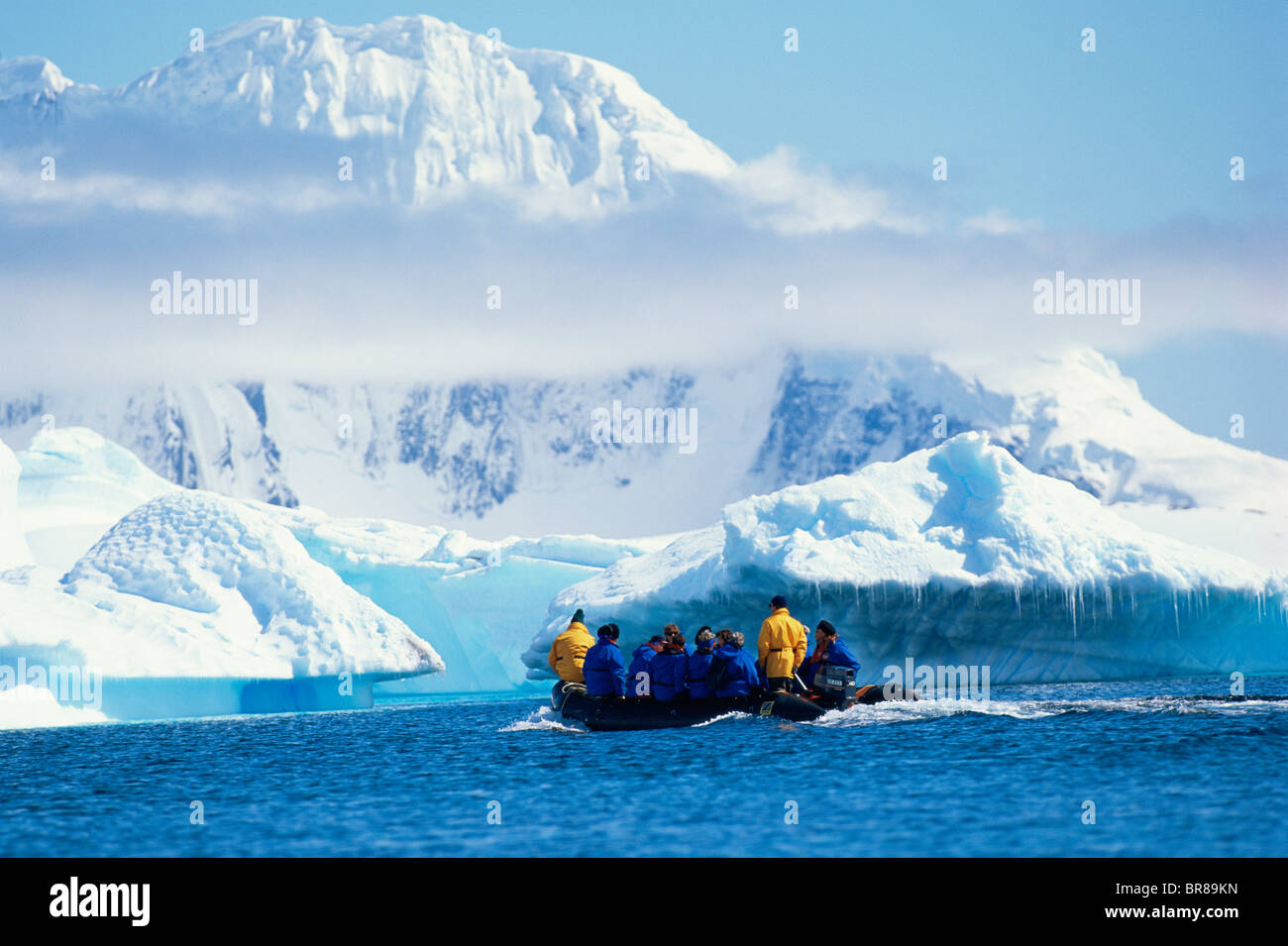Tourists In A Zodiac RIB In Front Of Icebergs With Low Cloud 