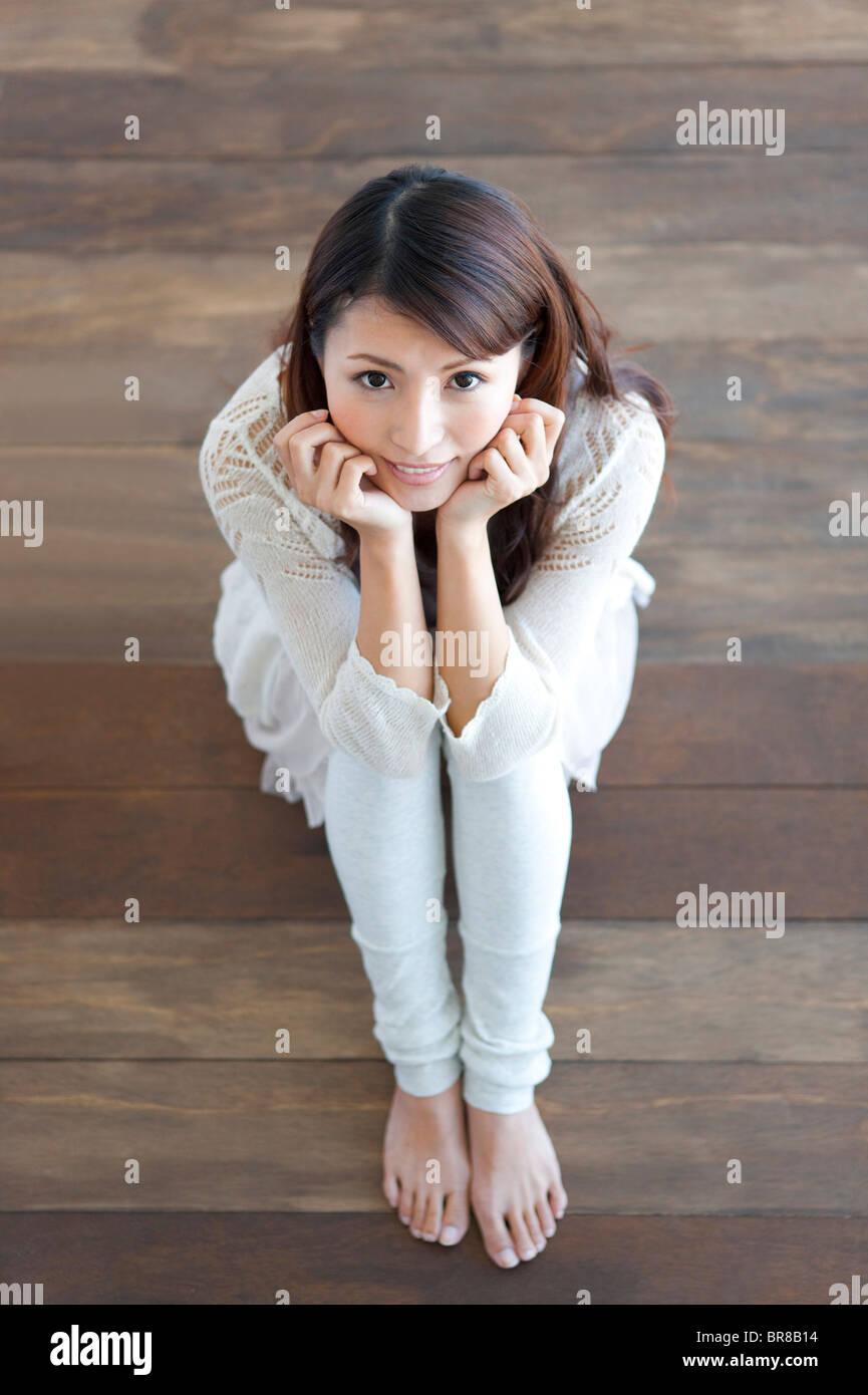Portrait of young woman sitting on floor, resting chin in hands Stock