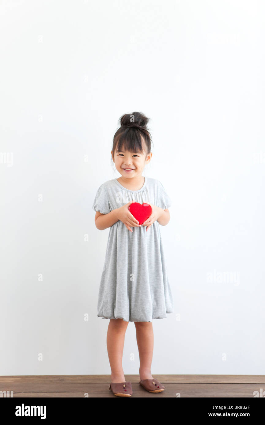 Portrait of girl holding red heart, white background Stock Photo - Alamy