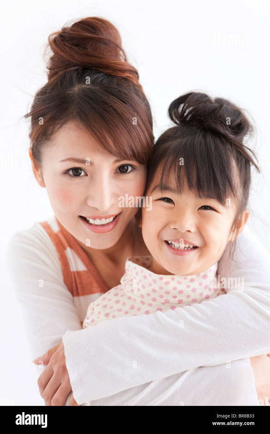 Portrait of woman embracing daughter, smiling, white background Stock ...