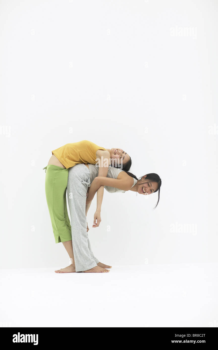 Two young women standing back to back bending over Stock Photo Alamy