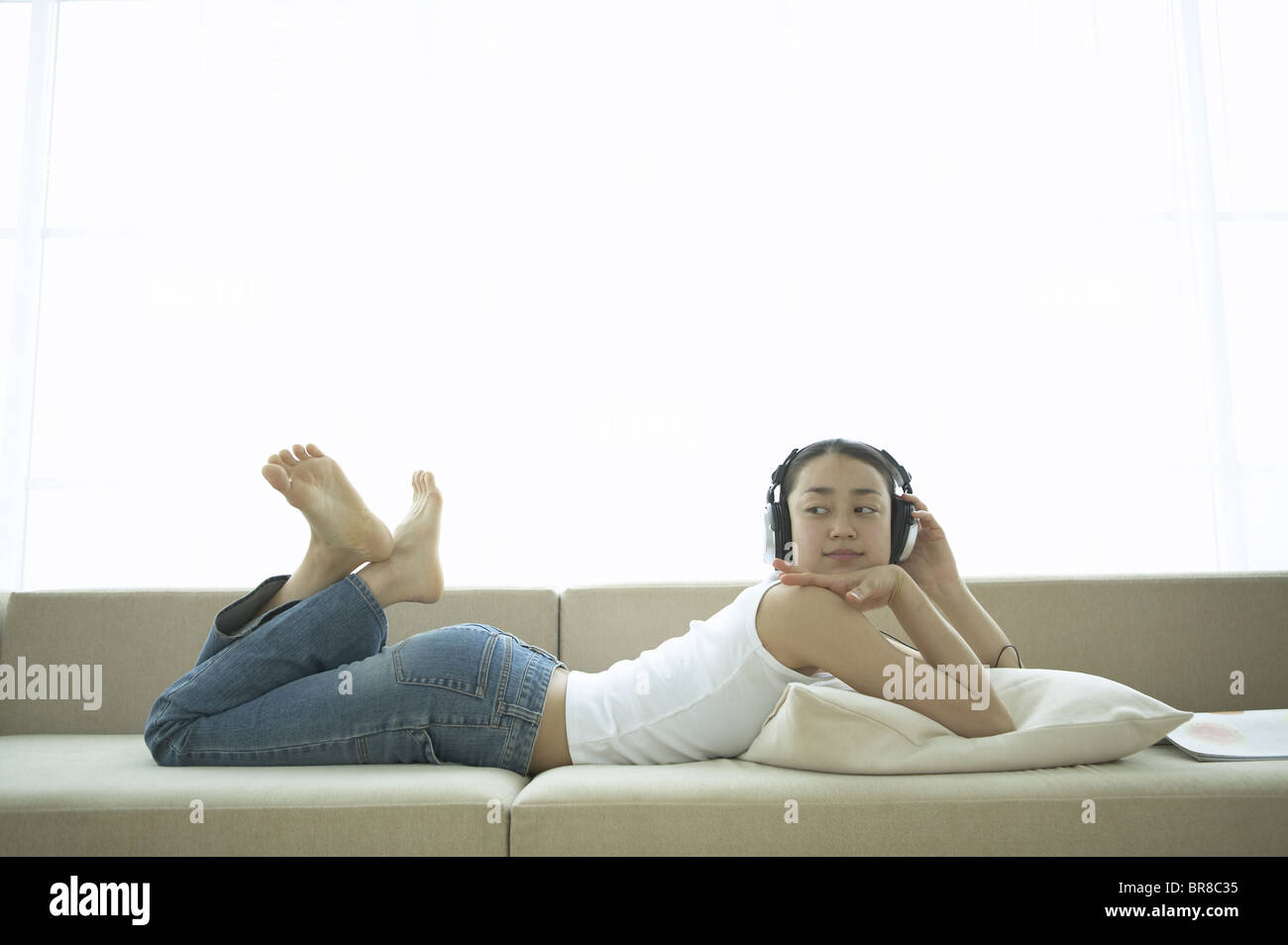 Young Woman Lying on Sofa, Listening to Music Stock Photo - Alamy