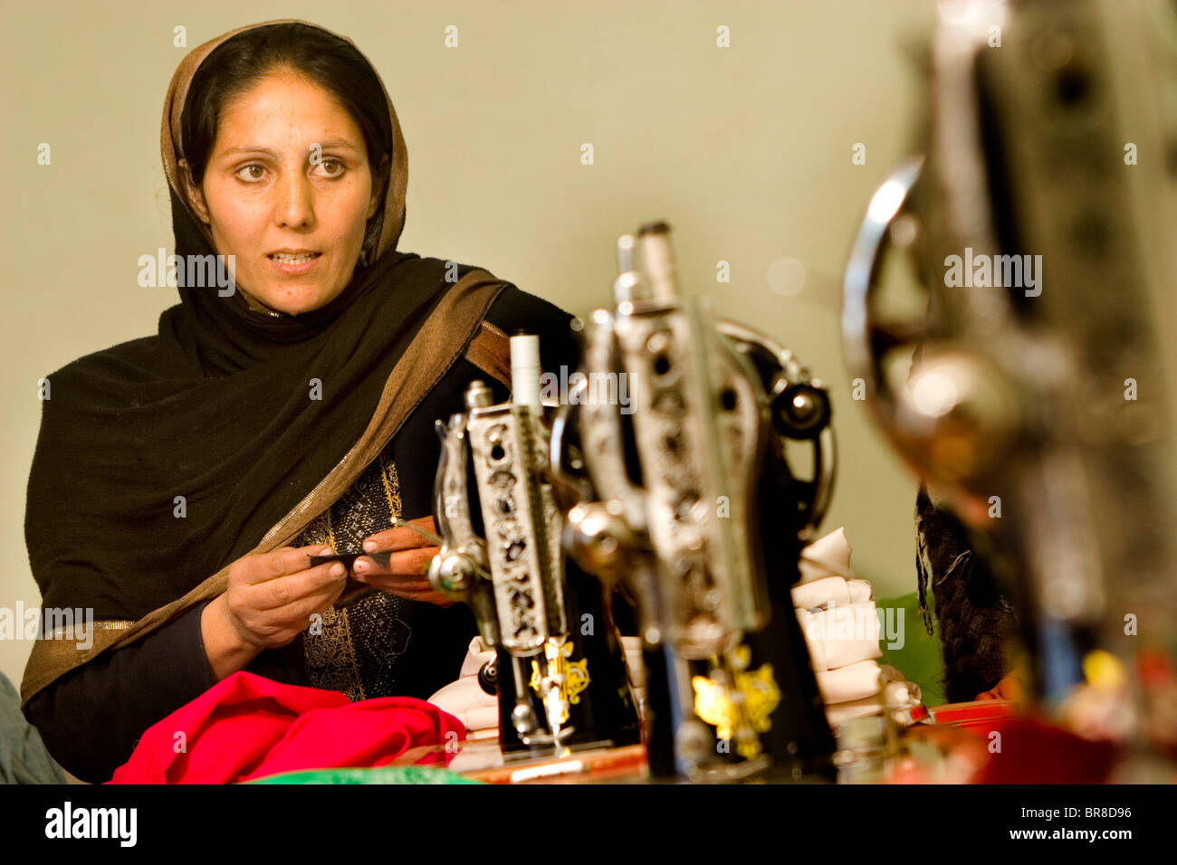 Afghan woman who runs a sewing stands near her sewing machines