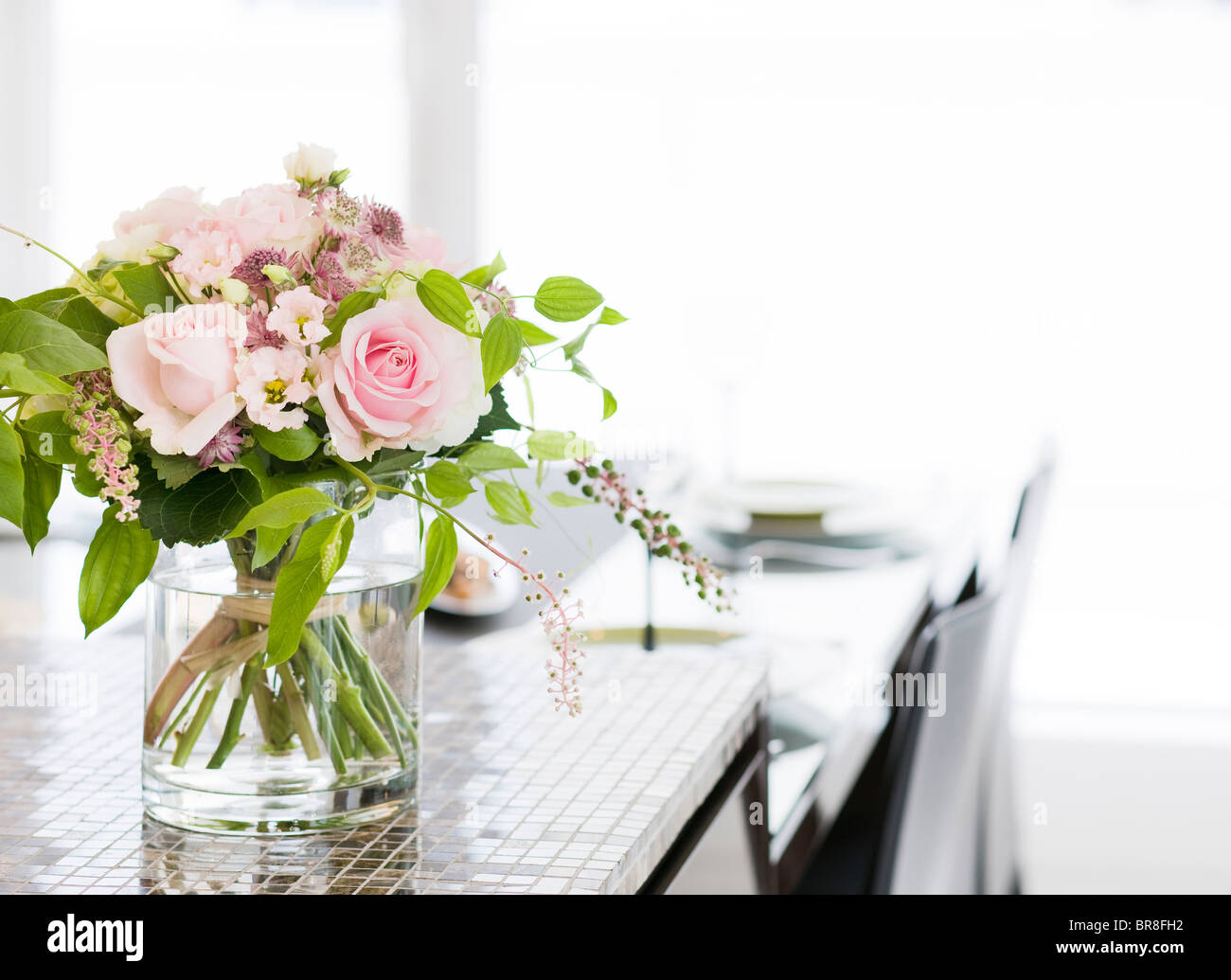 A Bunch of Flowers in a Vase at Dining Table Stock Photo