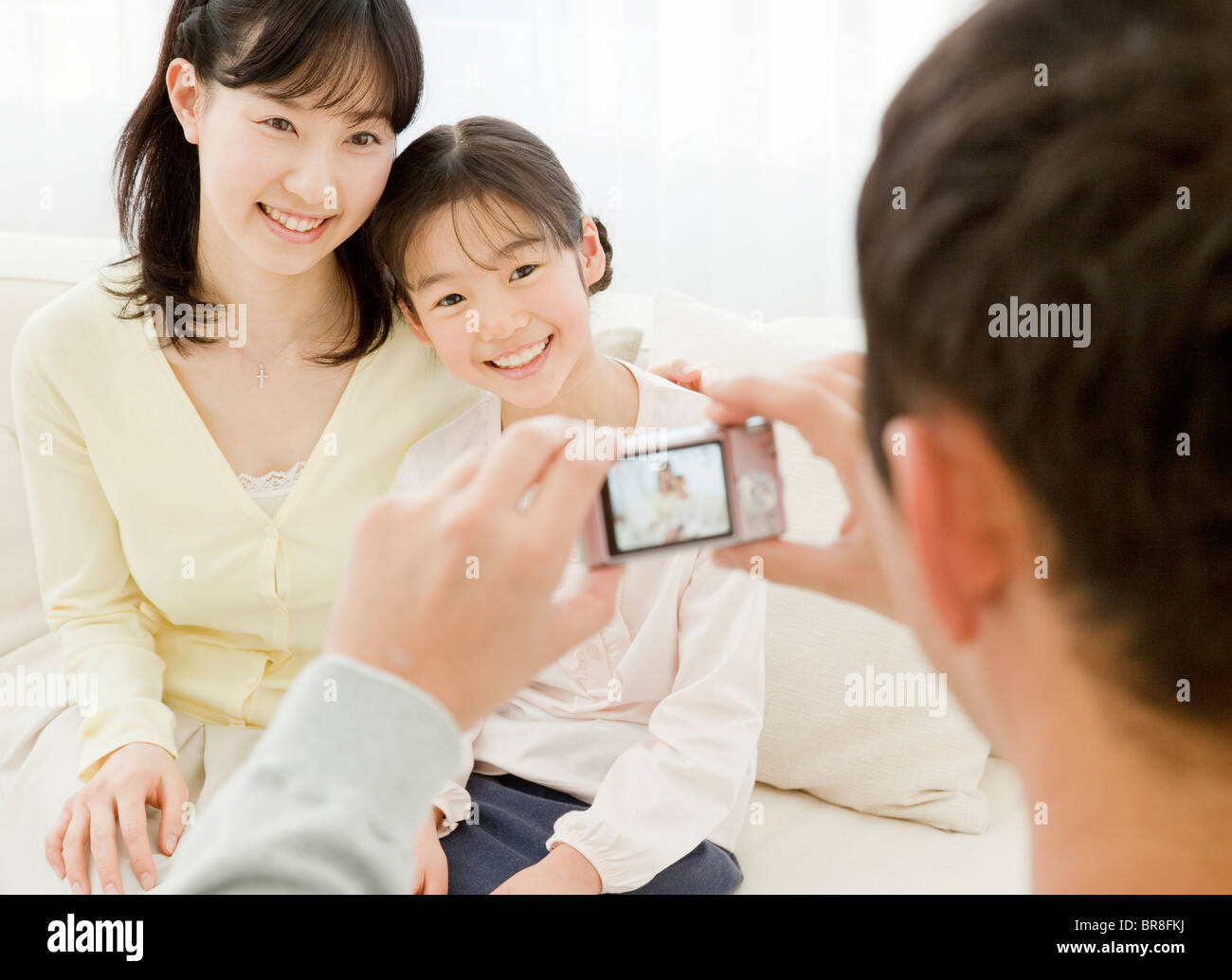 Father taking a photograph of mother and daughter Stock Photo