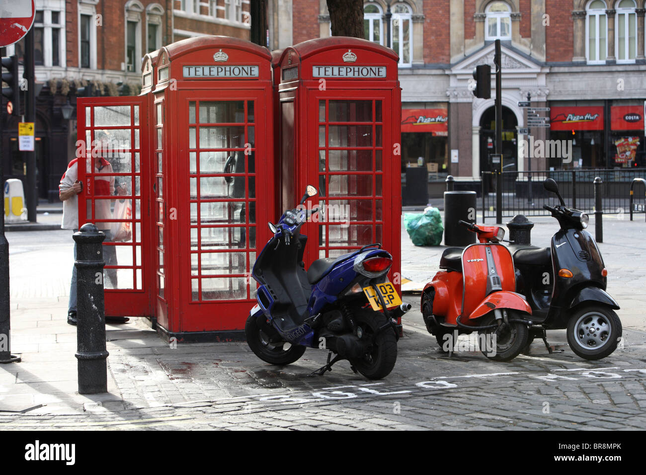 Scooters parked by phone booths in Charing Cross Road, Westminster, London, WC2. Stock Photo