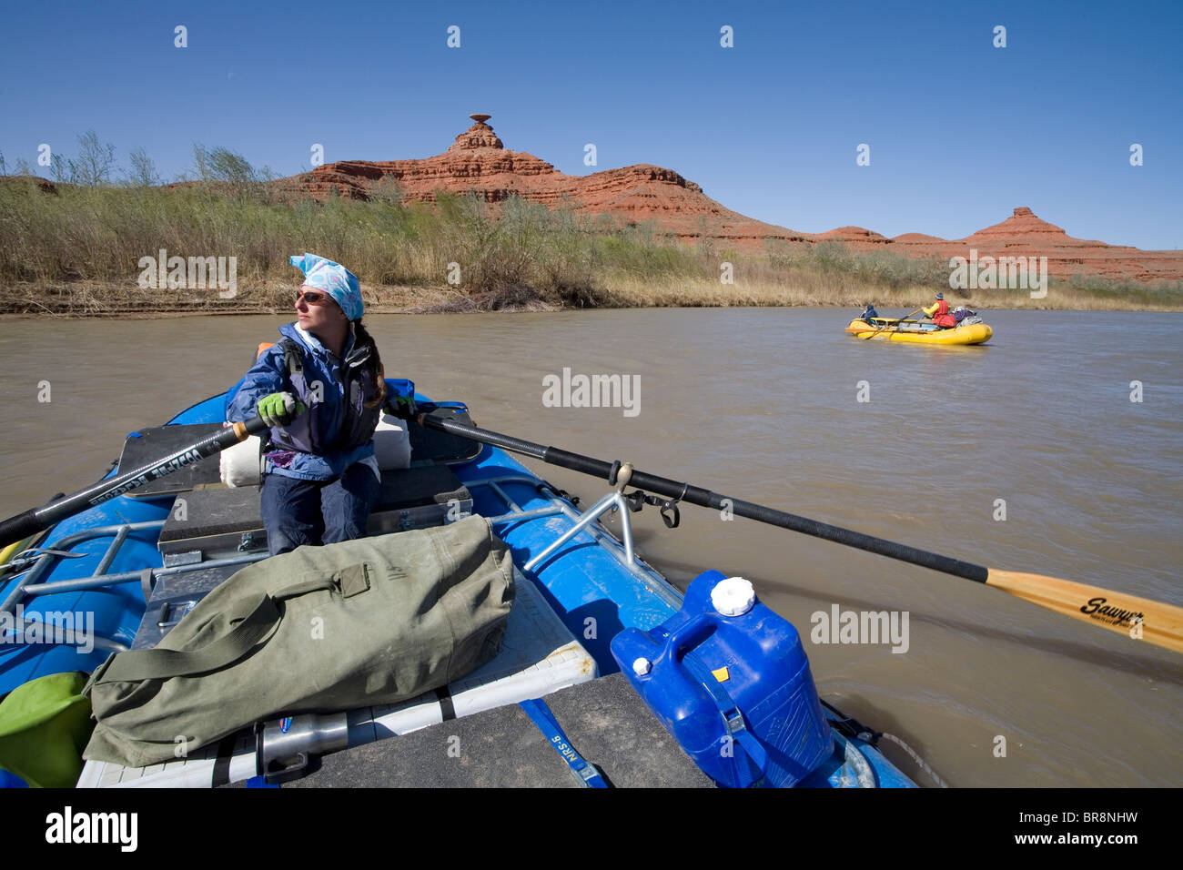 Woman rowing a raft down the San Juan river in Utah below the Mexican hat formation. Stock Photo