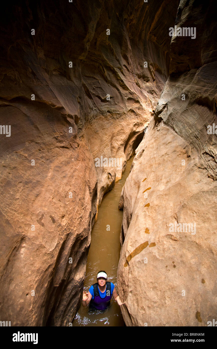 A woman wades though water in a desert slot canyon in Utah. Stock Photo