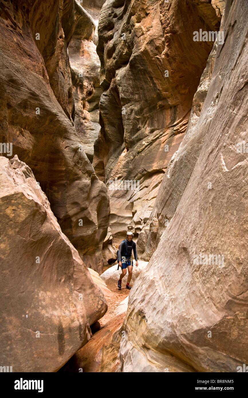 A man hiking down a slot canyon in the desert of Utah. Stock Photo