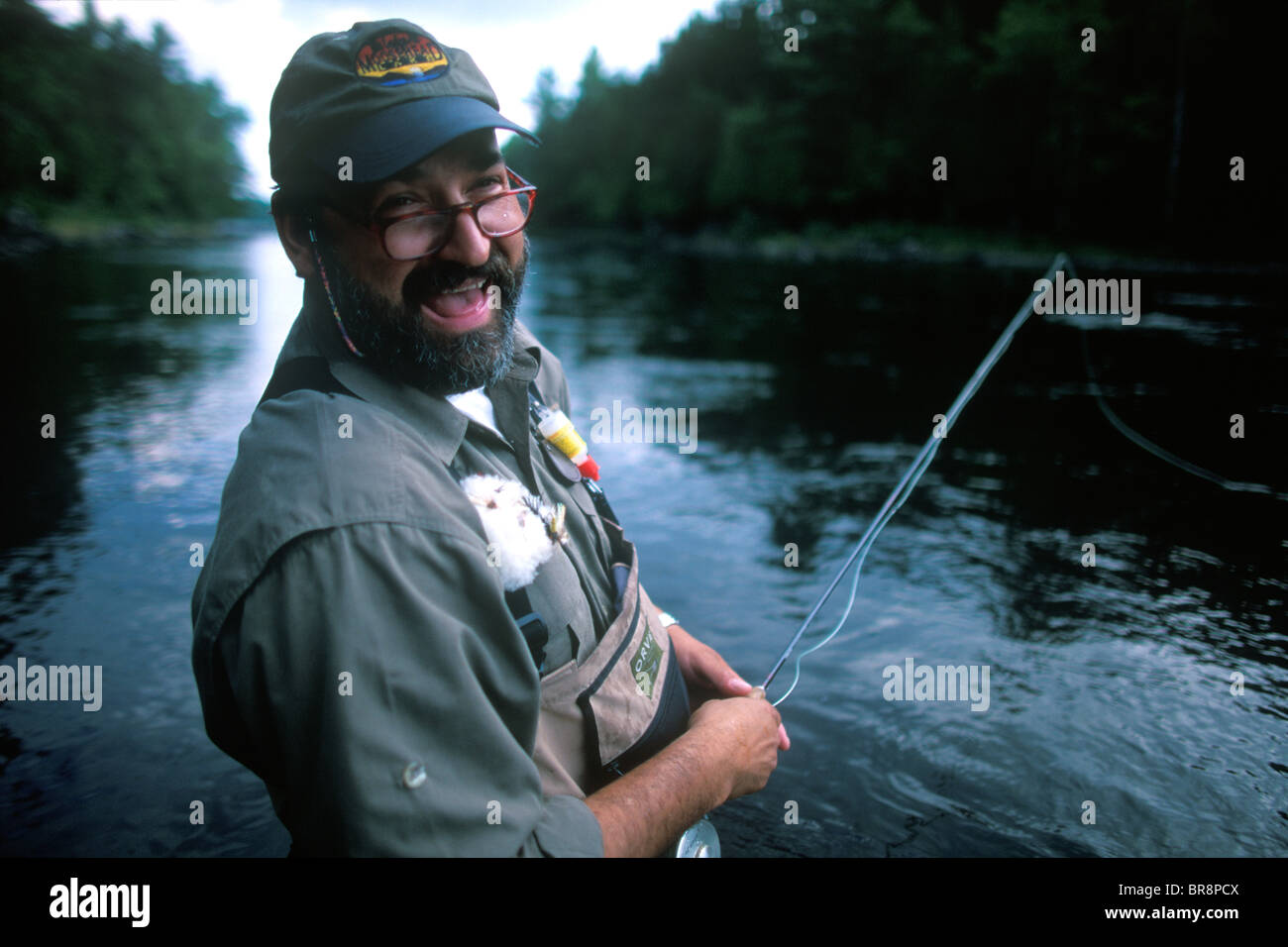 A fly fisherman smiles for the camera while fishing in the east outlet