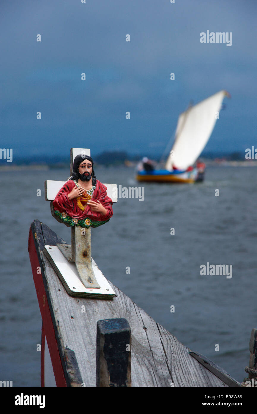 Cross with Jesus Christ  on a traditional Moliceiro boat bow with an out-of-focus Moliceiro boat in the background, Portugal Stock Photo
