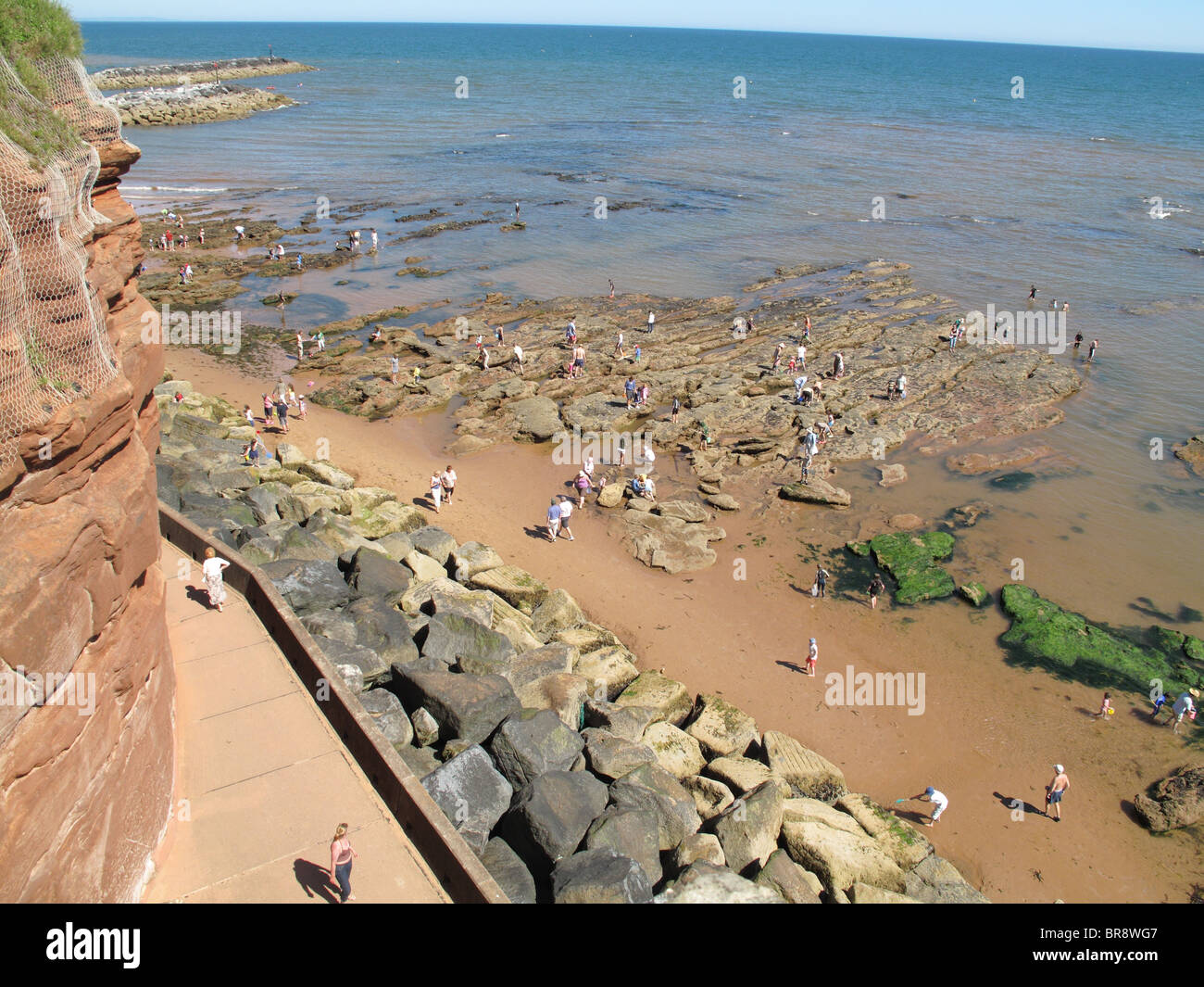 Rock pools and holiday makers at Sidmouth from Jacobs Ladder on a fine August summer day, Devon Stock Photo