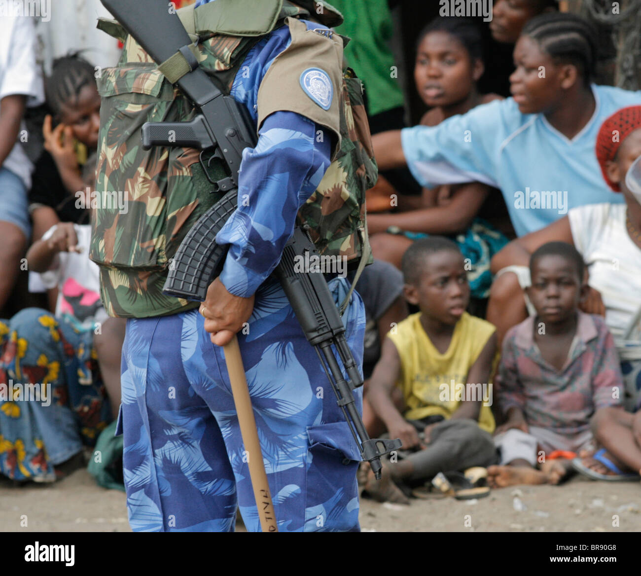 Peacekeeper with machine gun infront of group of kids Stock Photo