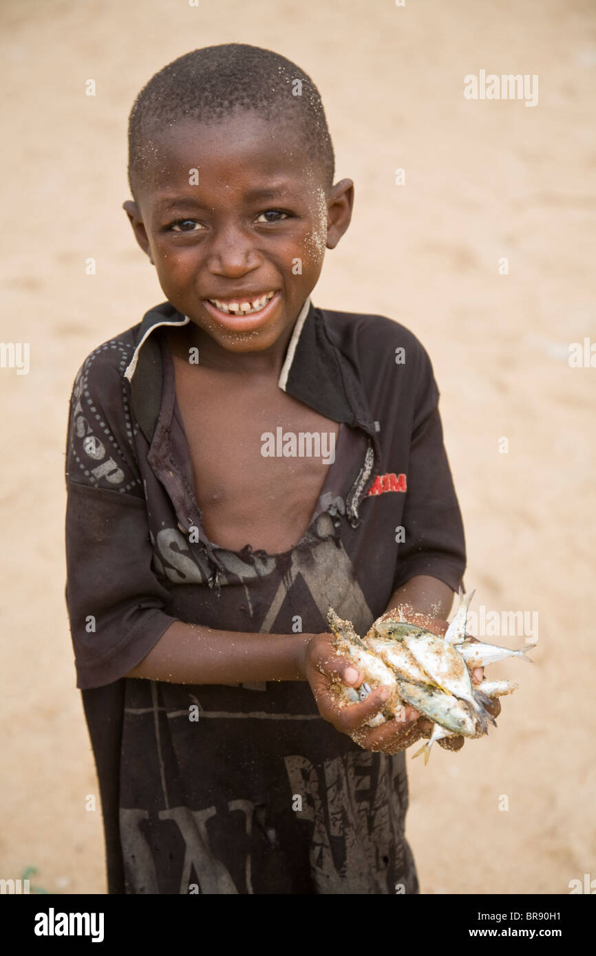 Young boy on a beach holding some fish Stock Photo