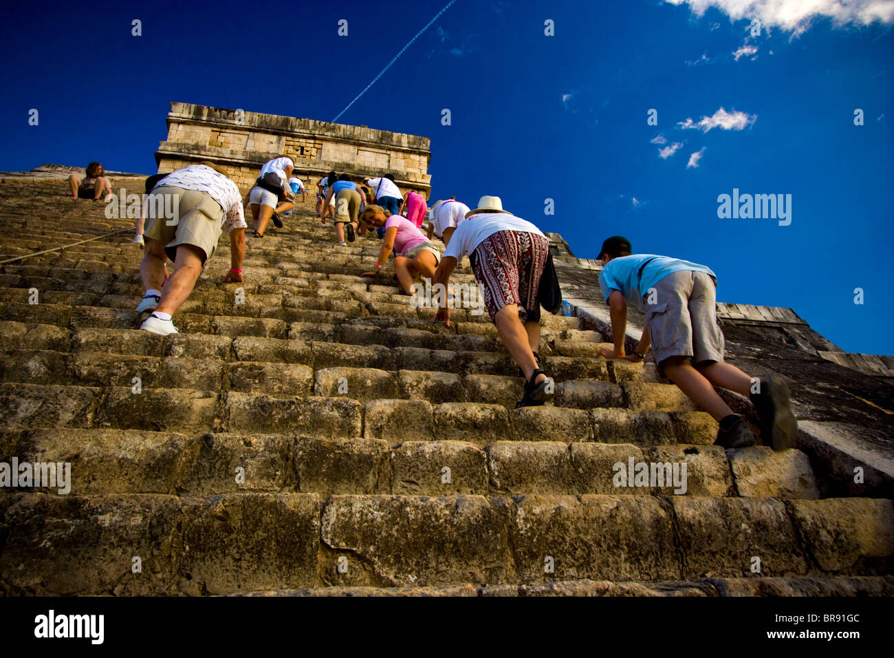 Visitors climb the steep steps of a ruin in Chichen Itza Mexico Stock
