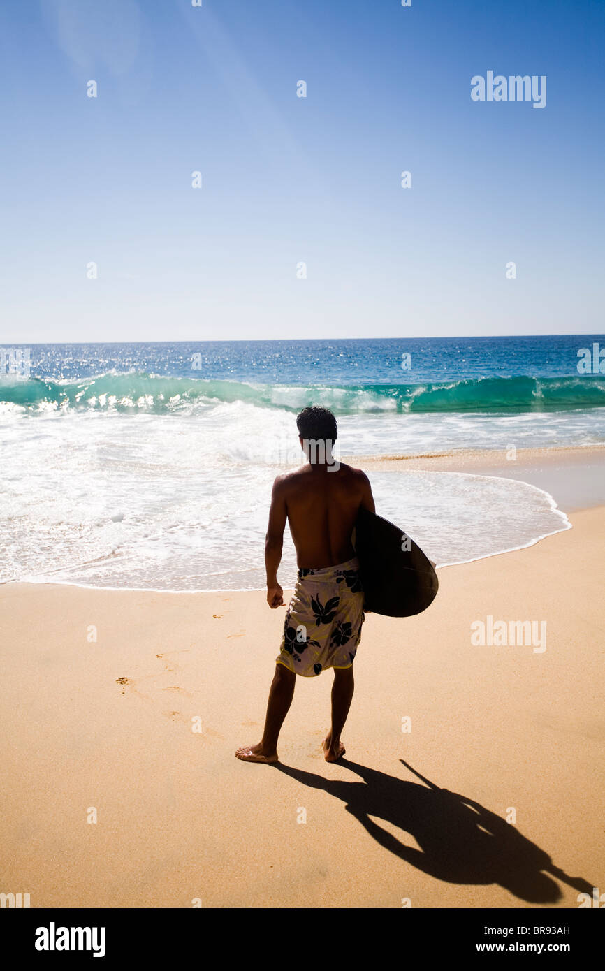A skimboarder/surfer looking at the waves in Cabo San Lucas Mexico Stock Photo