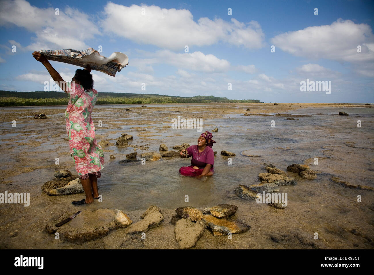 A woman dries her scarf while waiting for the tide to recede. Stock Photo