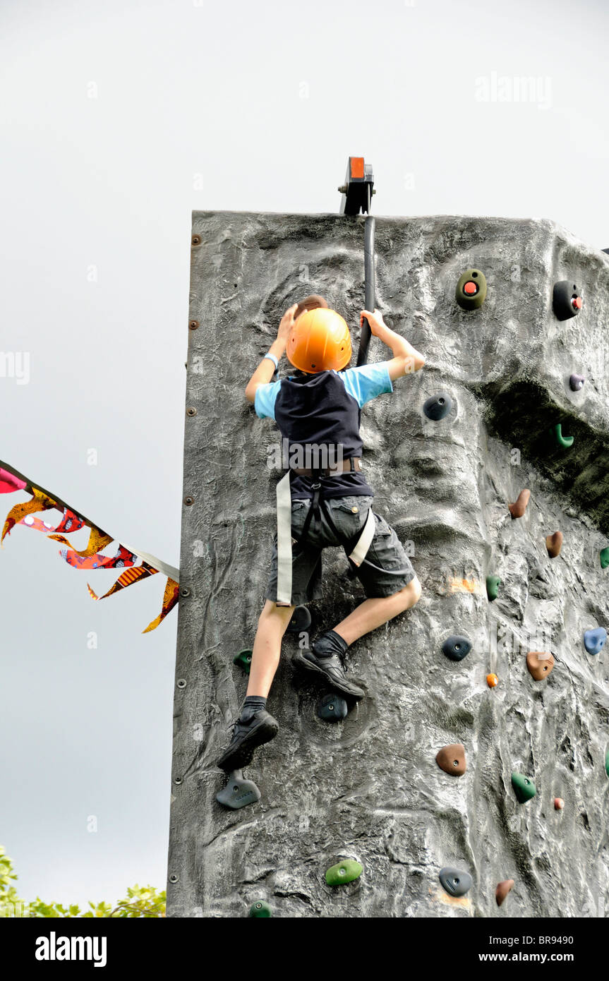 Young boy wareing helmet near the top of a freestanding climbing wall Stock Photo