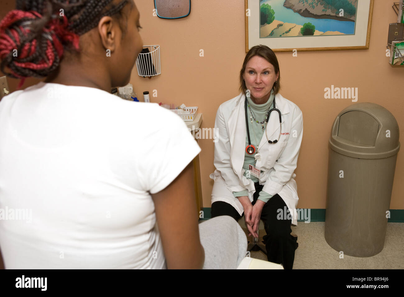 midwife in clinic, talking to pregnant teenage girl about pregnancy, choices, health, future, eating right, birth control, Stock Photo