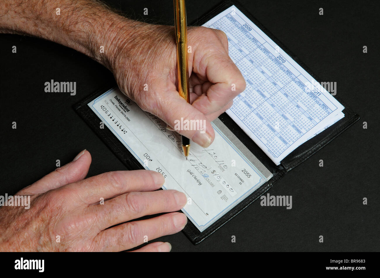 Elderly mans hands writing a Ten Thousand Dollar cheque from Independent National Bank Florida USA Stock Photo