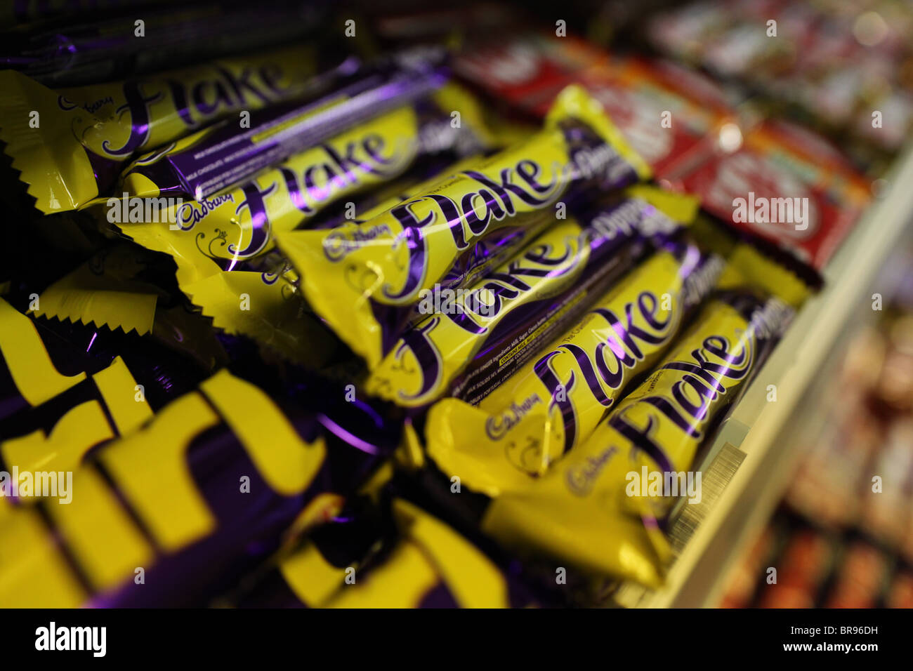 Cadbury Flake chocolate bars stacked on display in a UK convenience store. Iconic British confectionery brand packaging in close-up. Stock Photo