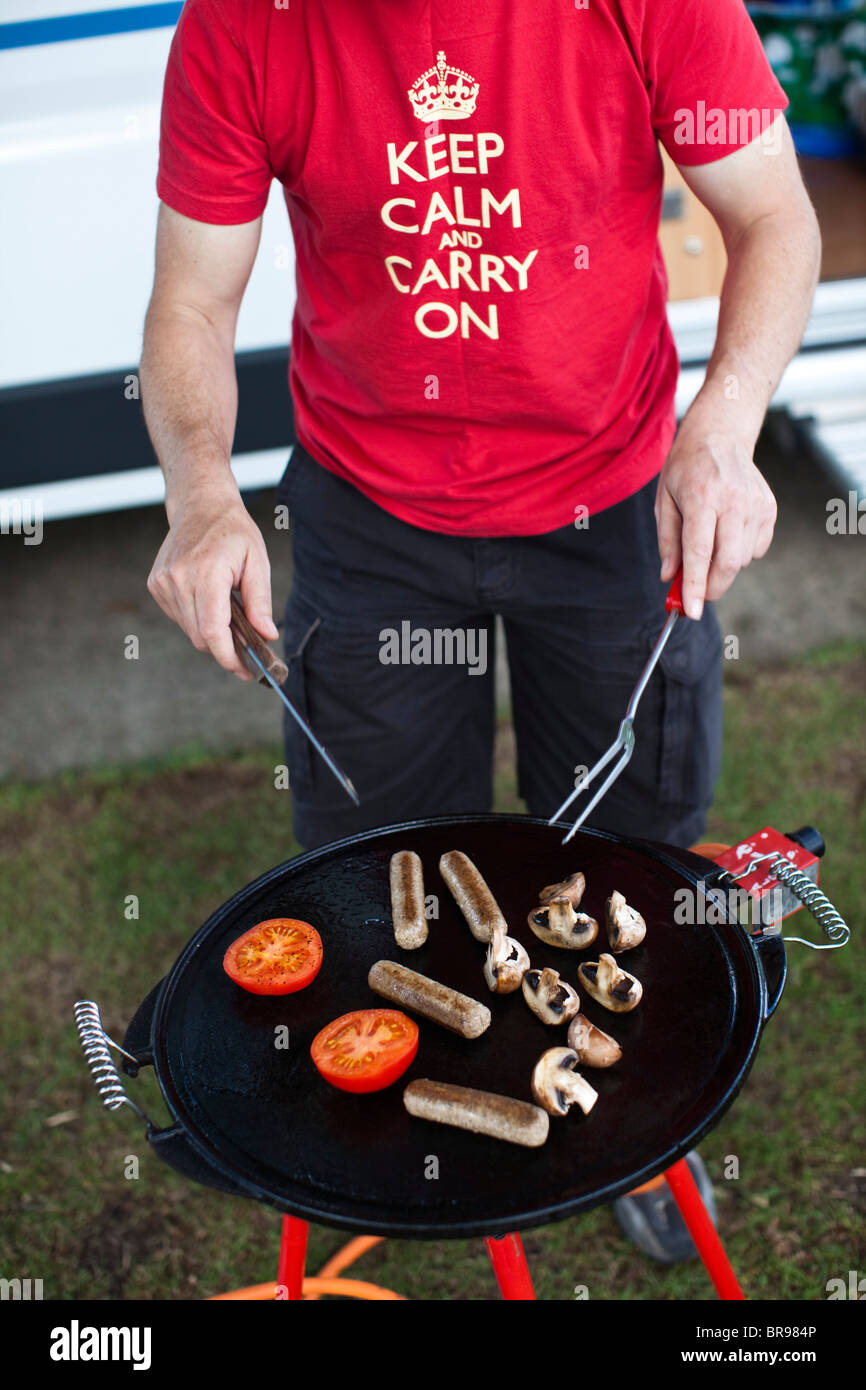 Man cooking breakfast on a portable stove outside his mobile home, UK. Stock Photo