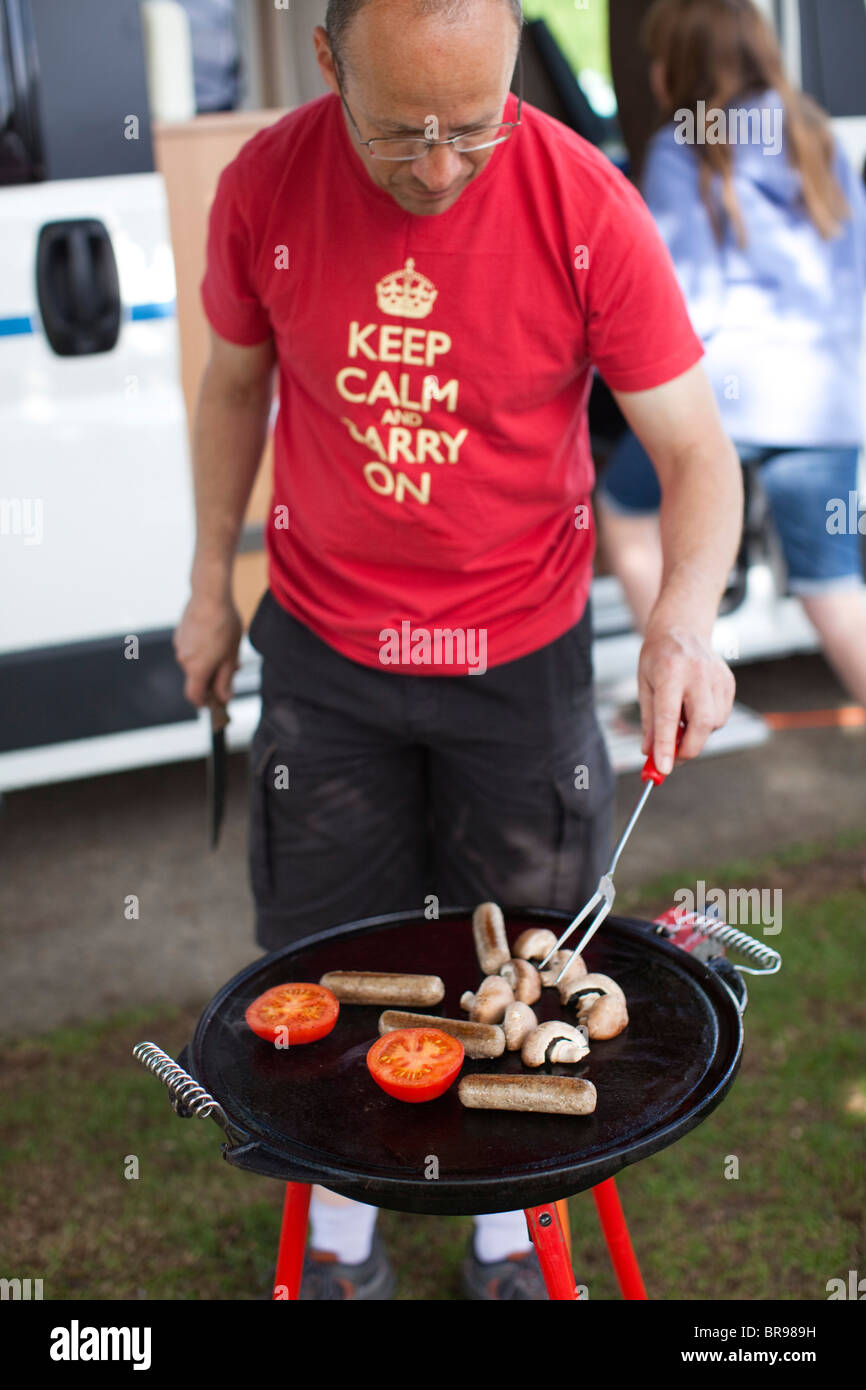 Man cooking breakfast on a portable stove outside his mobile home, UK. Stock Photo