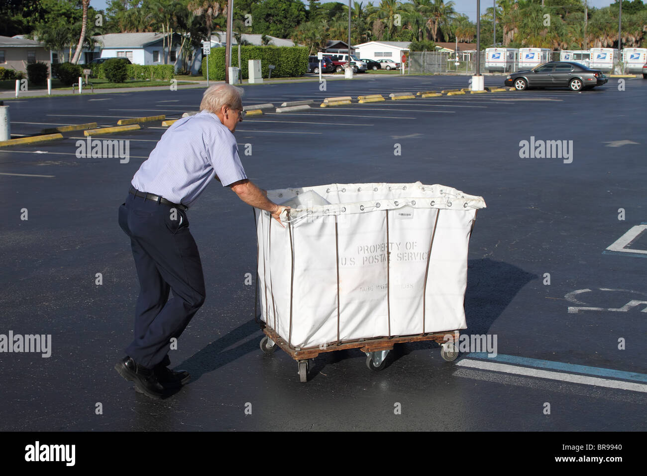 Post Office worker is pushing USPS cart with mail Stock Photo