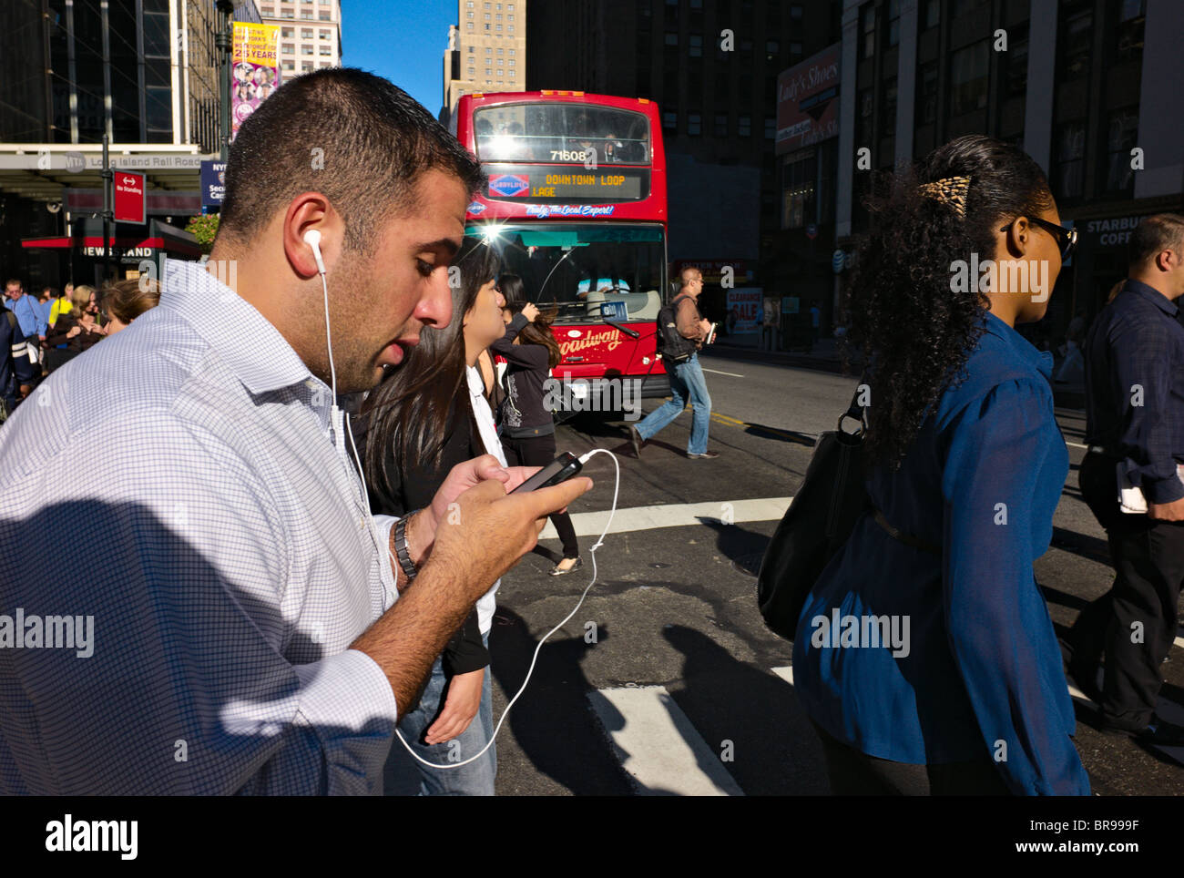 Man walking across crowded street while operating hand-held device. Stock Photo