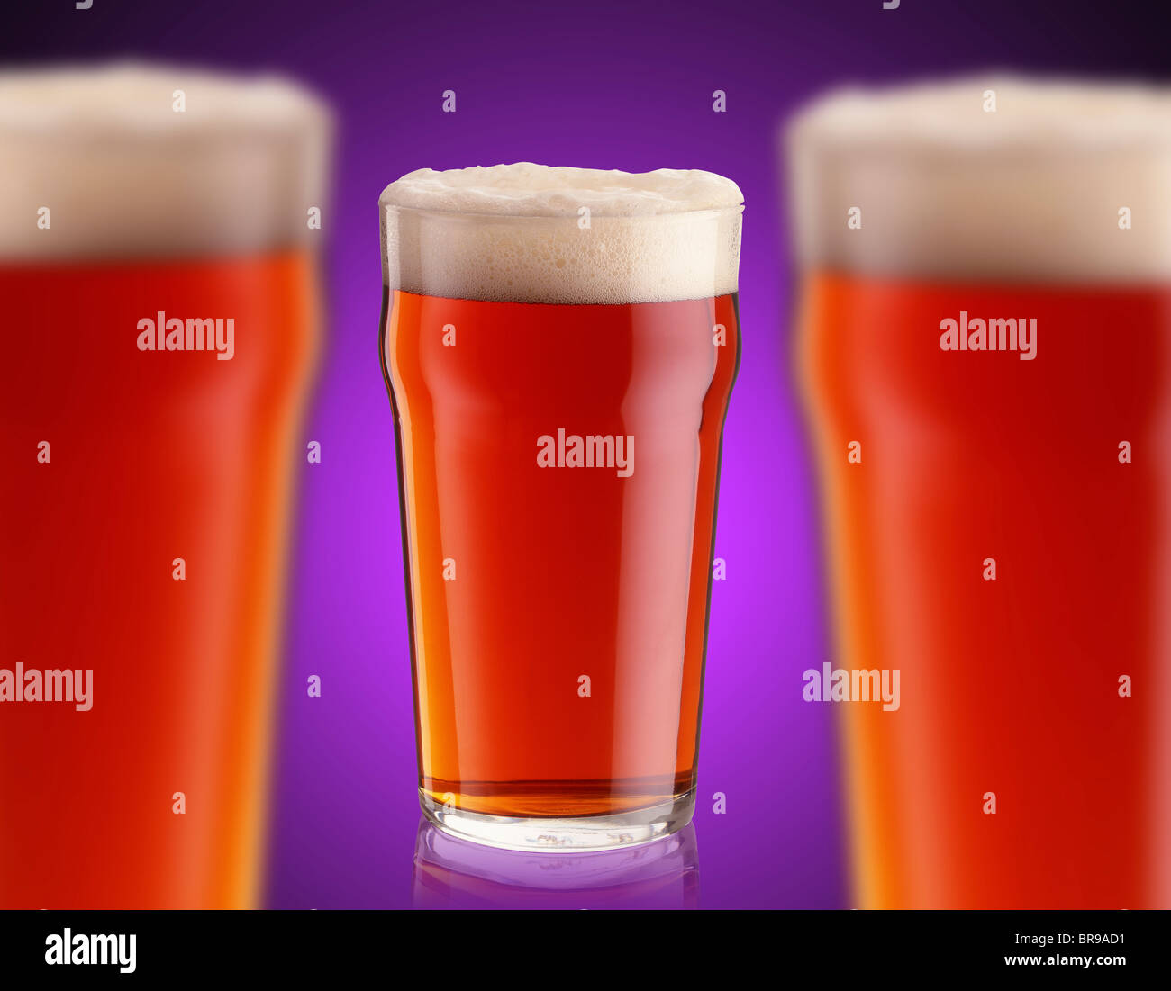 3 pints of bitter ale against a purple background Stock Photo