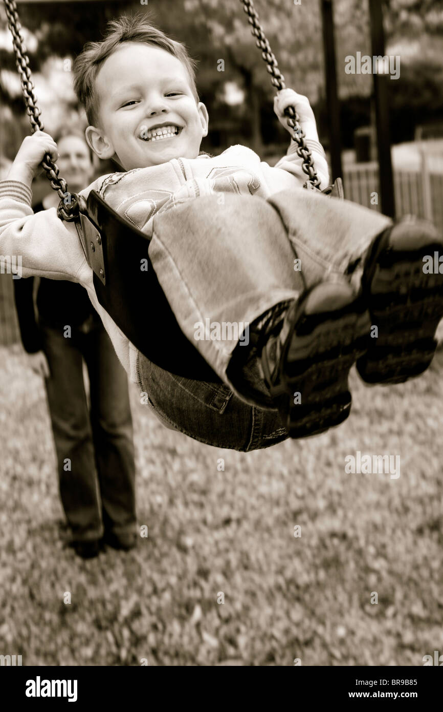 A little boy having a great time on a swing in a playground Stock Photo