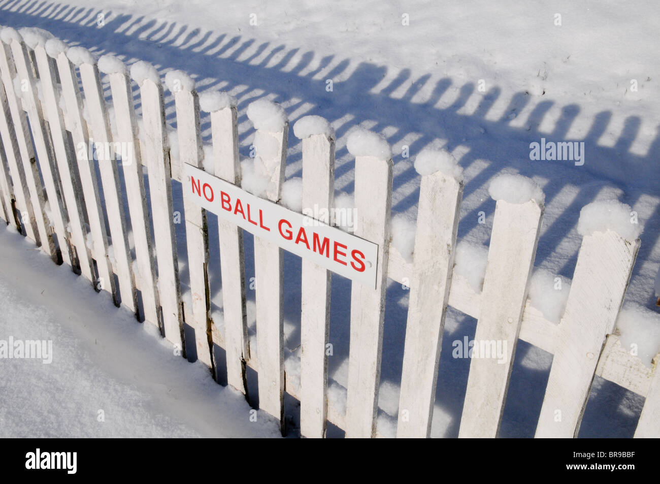 A red no ball games sign on a picket fence covered in snow at Wolverhampton Cricket Club Stock Photo