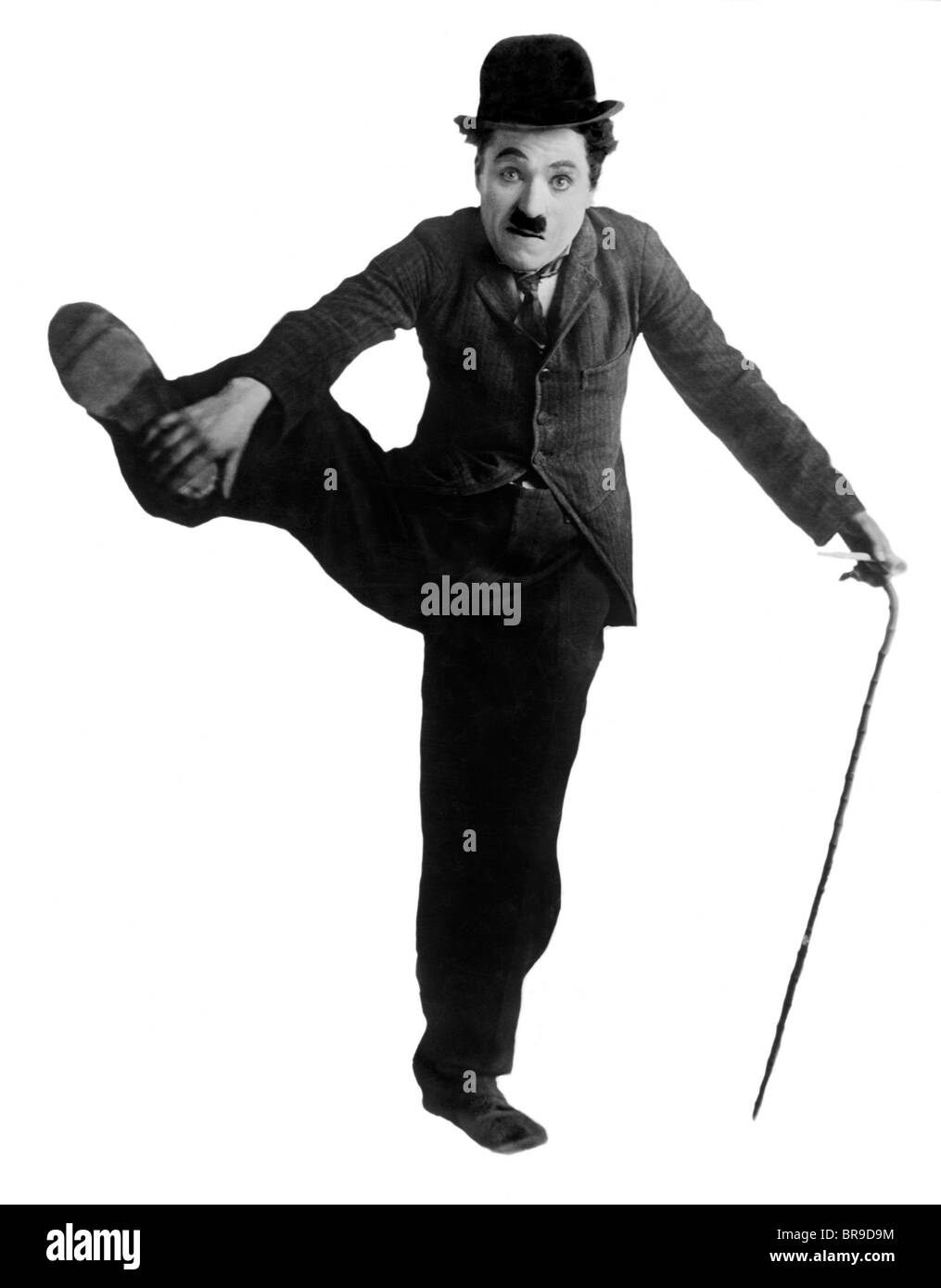 1910s CIRCA 1915 CHARLES CHAPLIN AS THE LITTLE TRAMP STANDING ON ONE LEG HOLDING OTHER UP WITH HAND Stock Photo