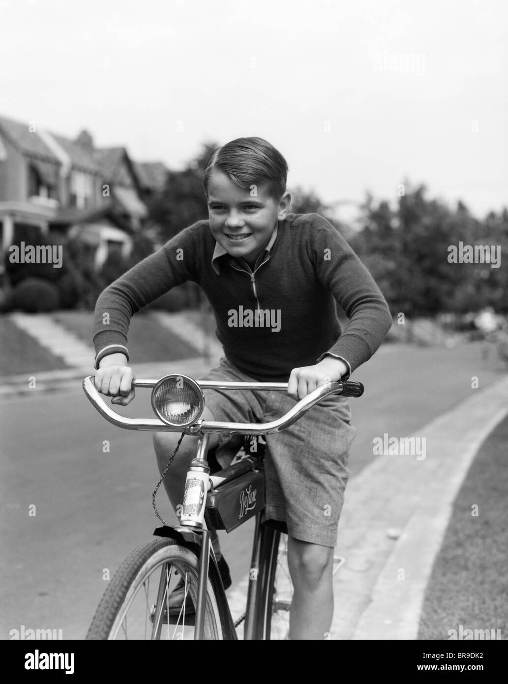 1930s SMILING BOY RIDING BICYCLE Stock Photo