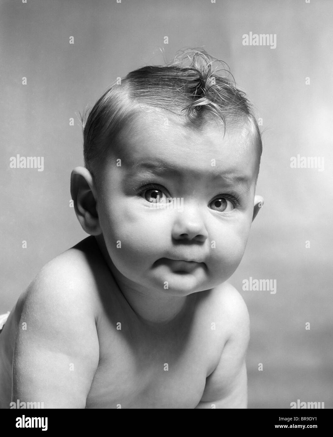 1950s CUTE SMIRKING BABY LOOKING AT CAMERA Stock Photo