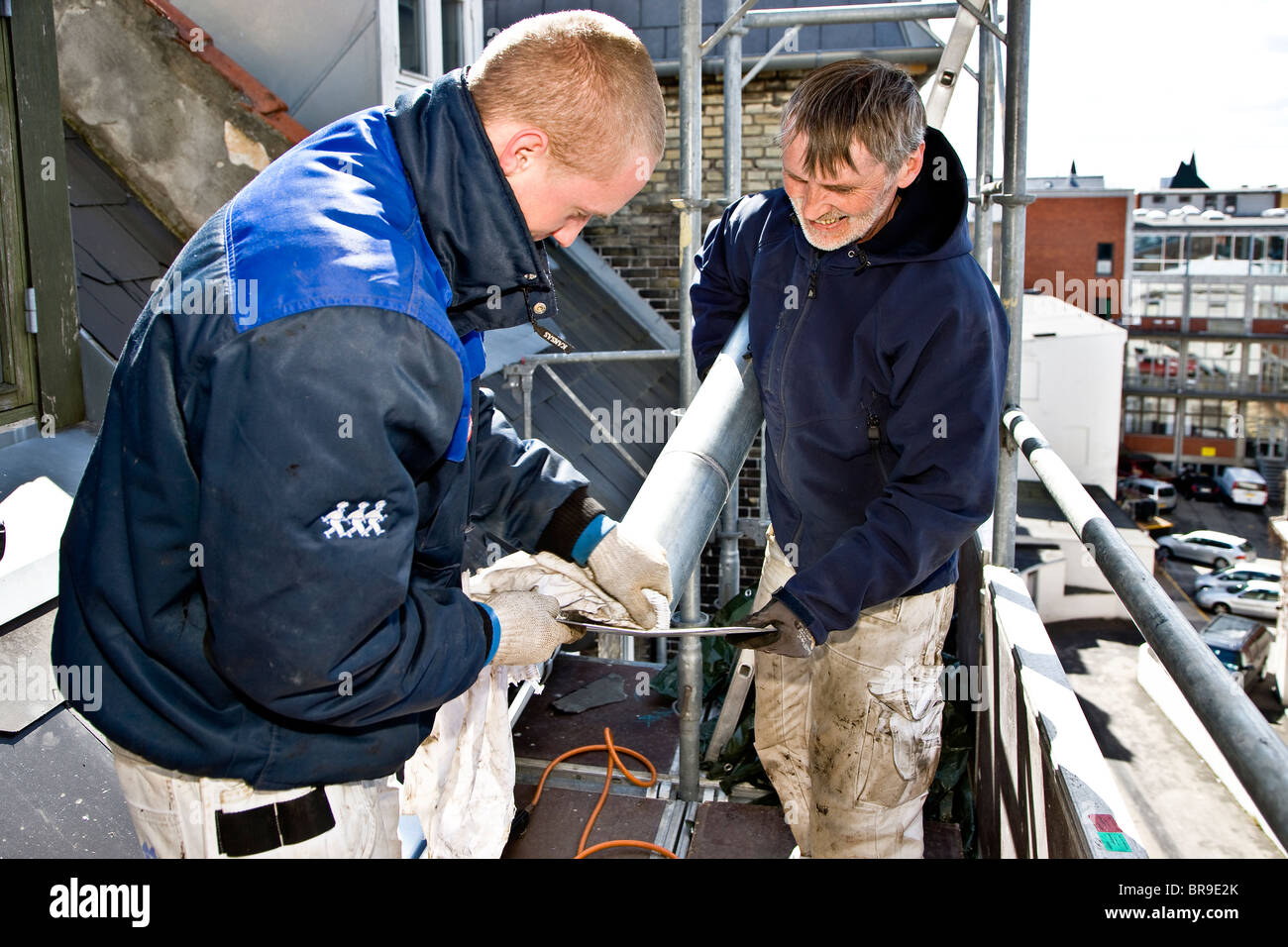 A plumber and his apprentice replace old leaky roof with new slates and