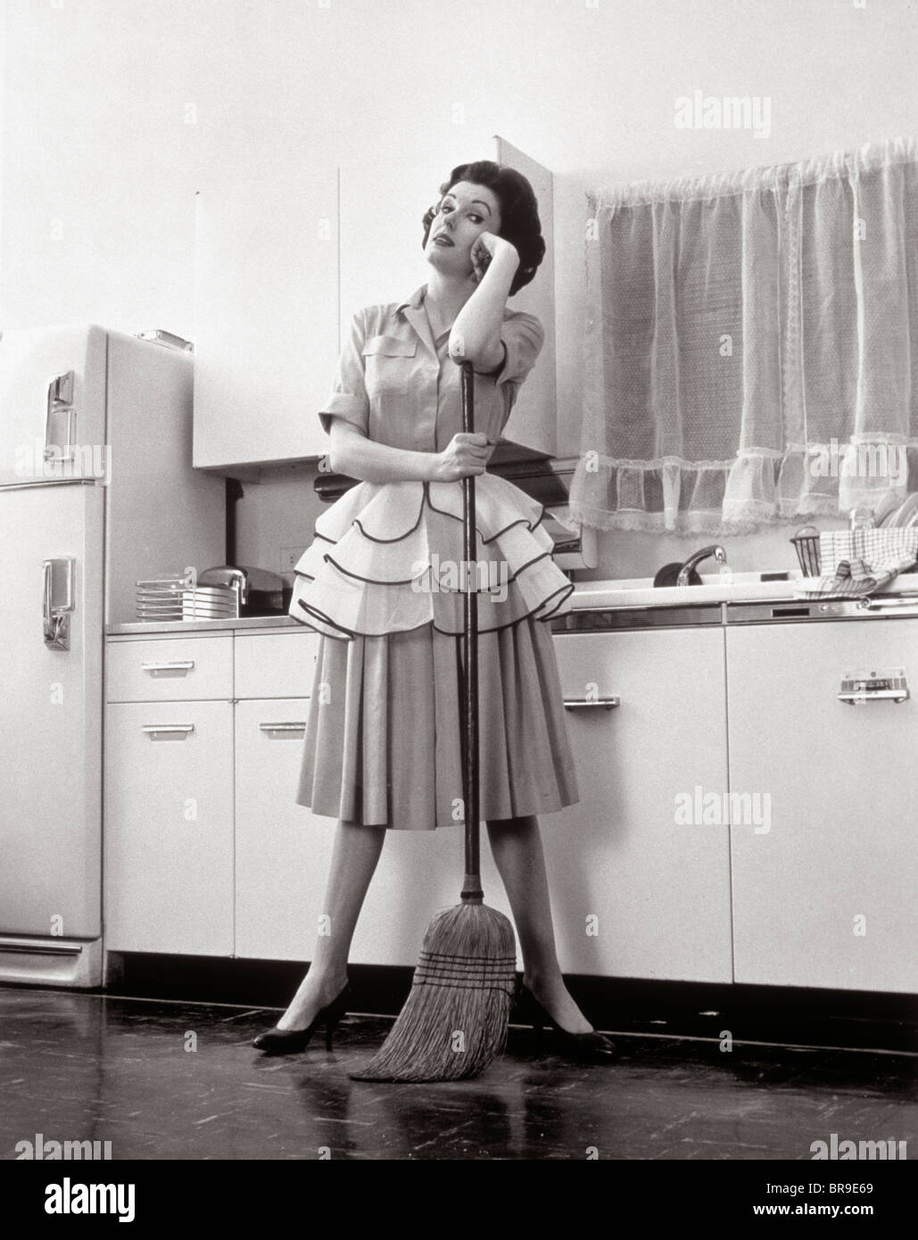 1950s WOMAN HOUSEWIFE STANDING IN KITCHEN LEANING ON BROOM Stock Photo -  Alamy
