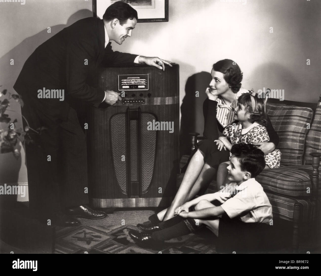 1930s FAMILY LISTENING TO RADIO FATHER TUNING CHANNEL MOTHER CHILDREN  SITTING COUCH Stock Photo - Alamy