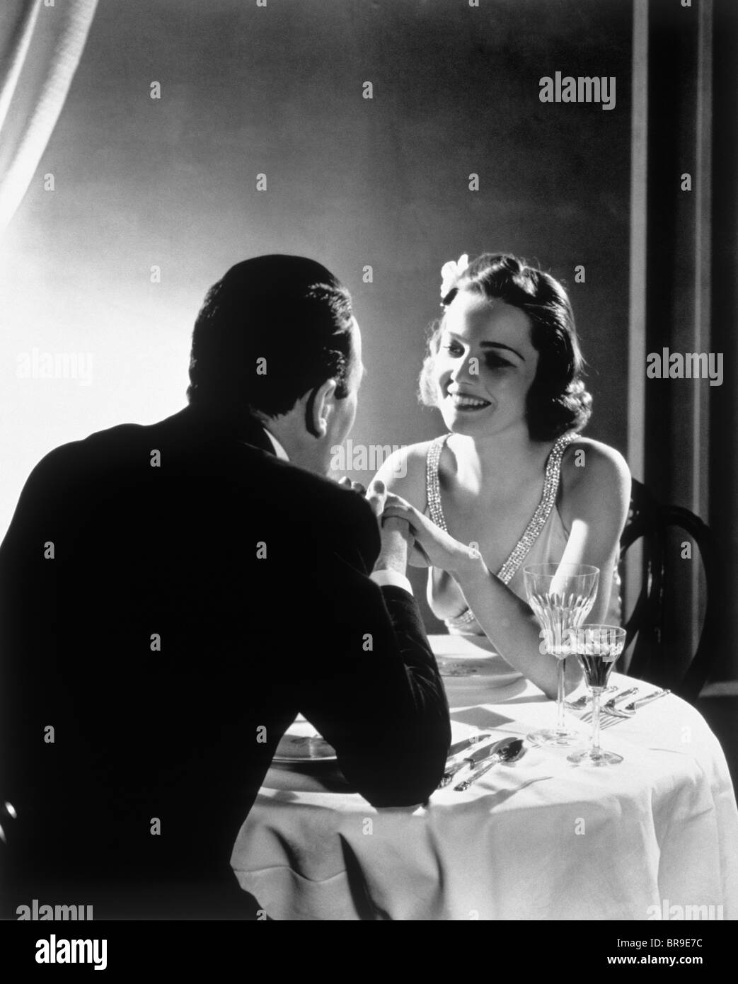 1930s ROMANTIC COUPLE MAN WOMAN ELEGANT DINNER TABLE Stock Photo