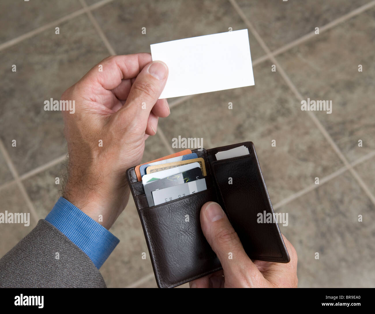 man holding his wallet and extending a blank business card Stock Photo
