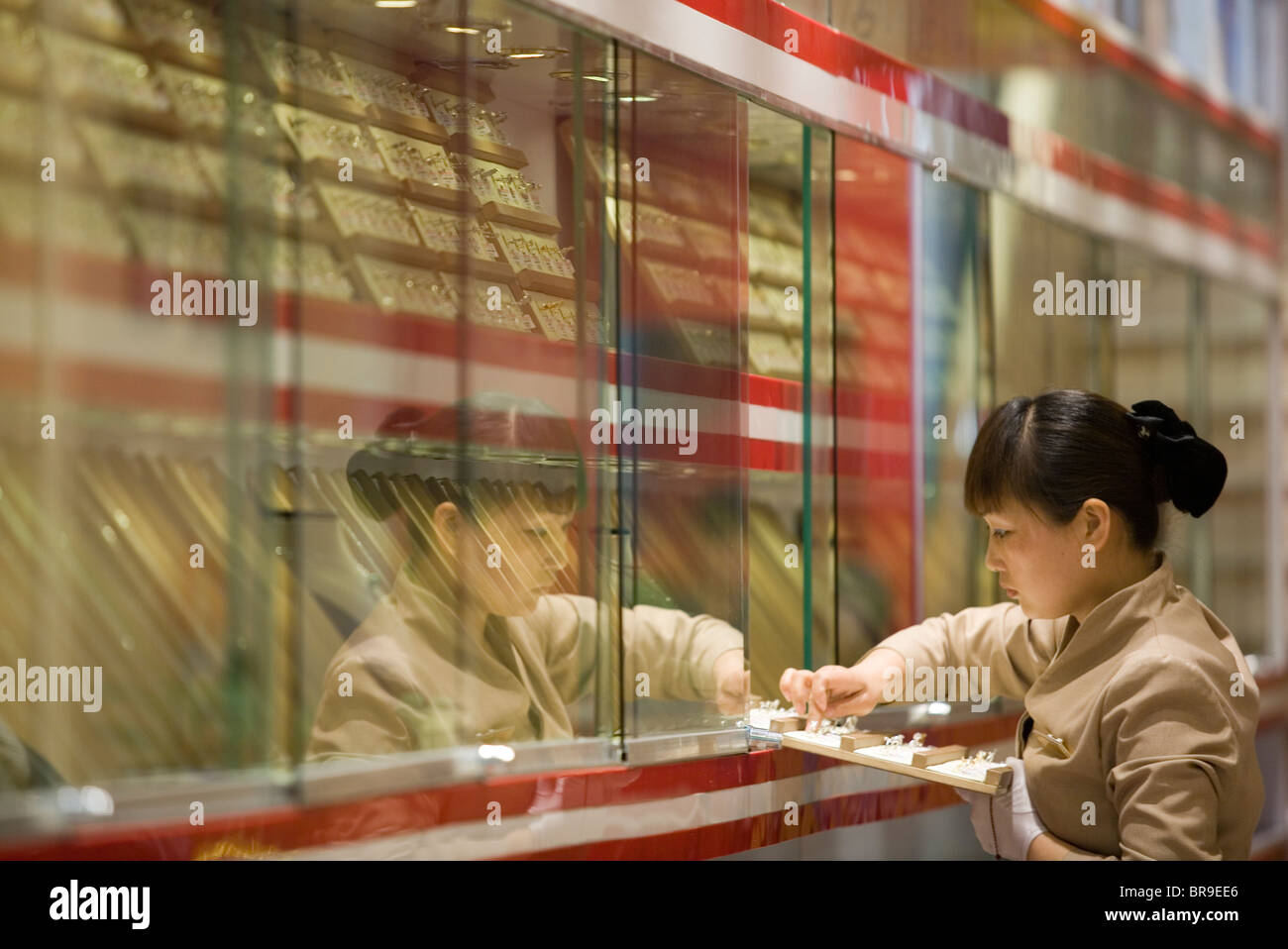 Shop clerk arranges gold jewelry in Xian China. Stock Photo