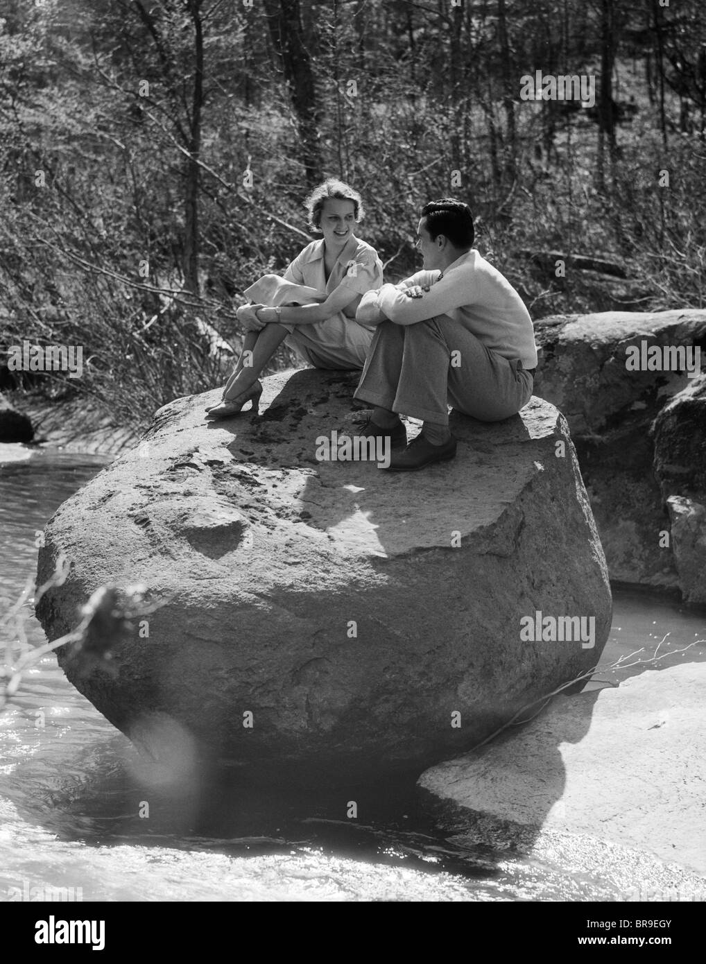 Man Hugging Rocks 1930s COUPLE MAN WOMAN SITTING ON LARGE ROCK IN STREAM HUGGING KNEES ...