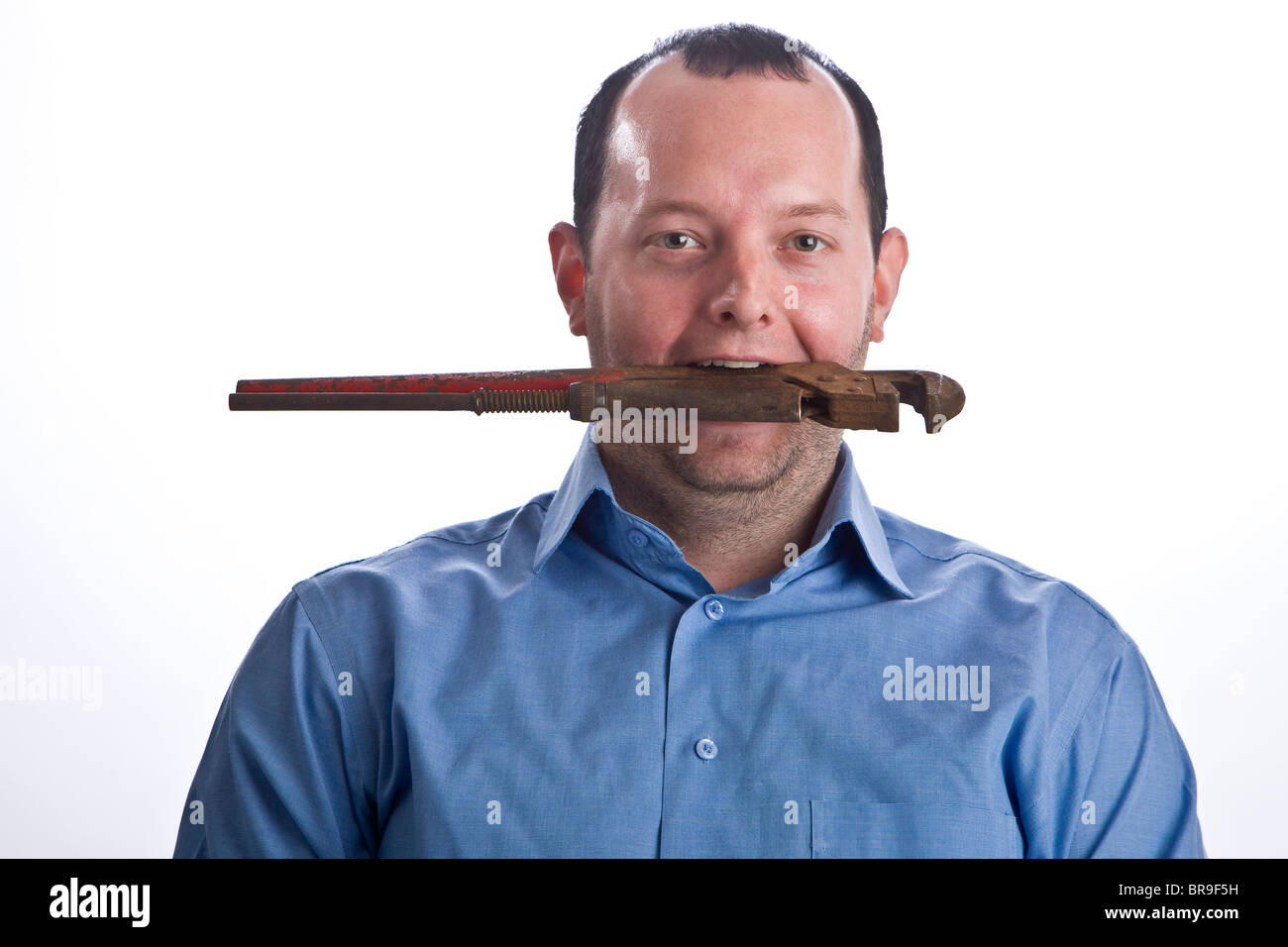 Young heating and sanitary technician with a pipe wrench in his mouth Stock Photo