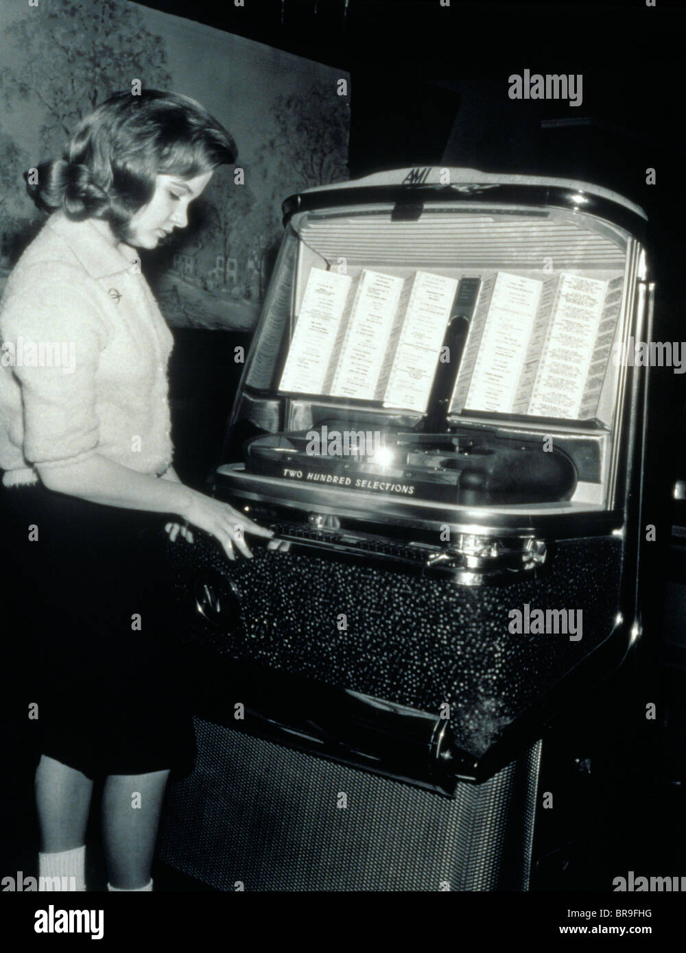 1950s TEENAGE GIRL SELECTING MUSIC ON COIN-OPERATED JUKEBOX Stock Photo